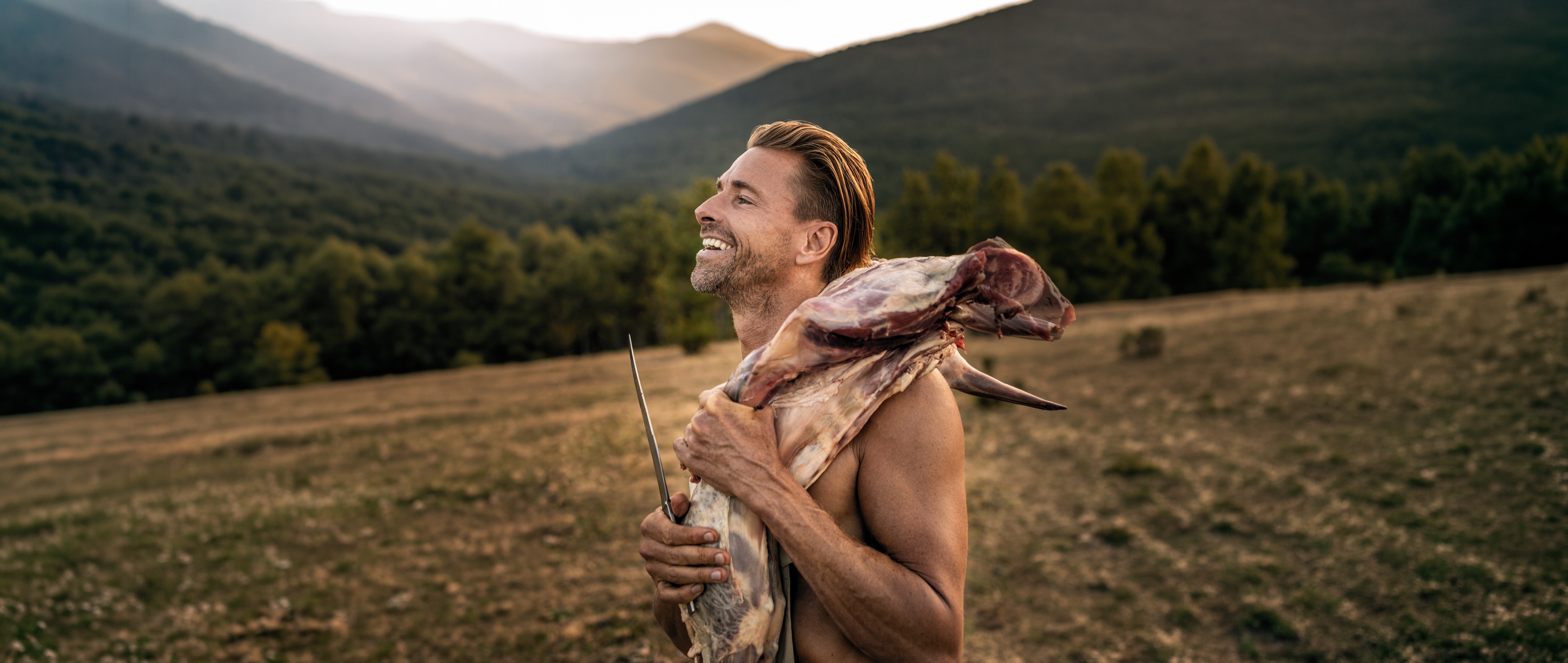Niklas Gustafson standing in a mountain landscape with wild game over his shoulder