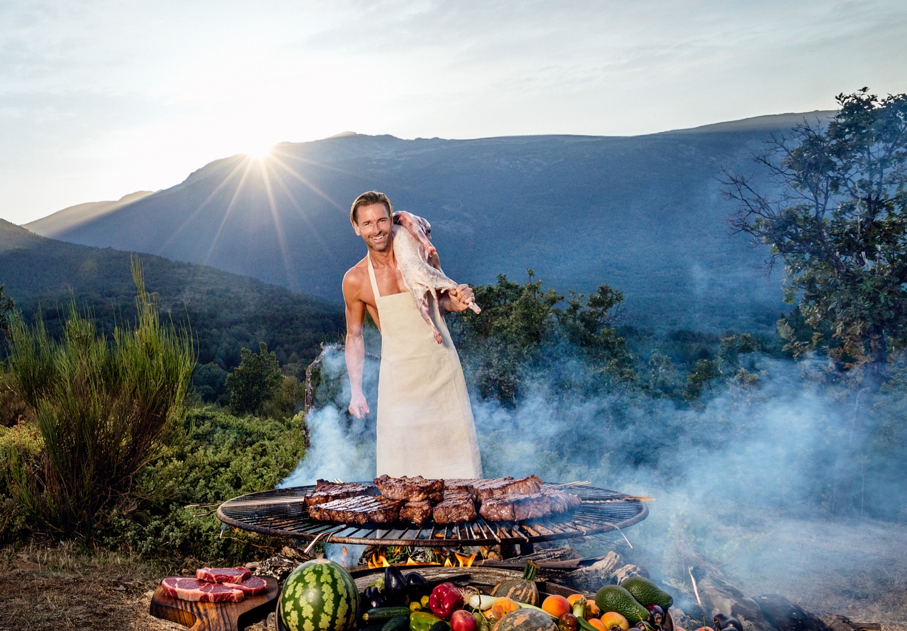 Niklas cooking over an open fire in the mountains at sunset